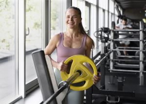 mulher na academia ajeitando um peso na barra